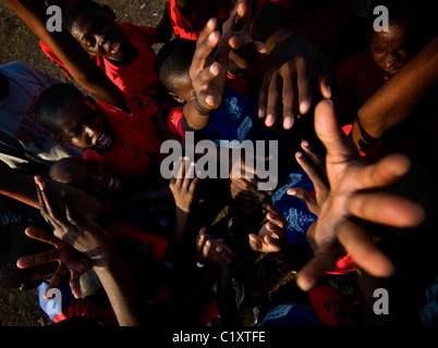 De jeunes enfants tendent la main pour obtenir des bouteilles d’eau distribuées par la Croix-Rouge dans le camp Jean Marie Vincent qui accueille des milliers de personnes depuis que le séisme de magnitude 7,0 a frappé Haïti le 12 janvier 2010 Banque D'Images