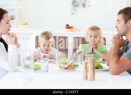 Portrait d'une famille prier ensemble au cours du déjeuner Banque D'Images