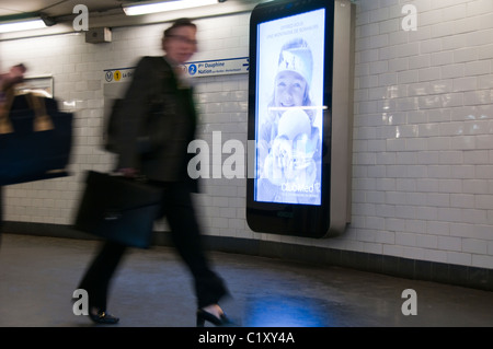 Paris, France, femme marchant dans le système de transport en commun, station de métro, couloir intérieur, près de l'affiche de publicité électronique interactive française sur l'affichage, panneaux d'affichage intelligents, solitude. Image conceptuelle de la solitude représentée par la silhouette d'une femme marchant dans un couloir Banque D'Images