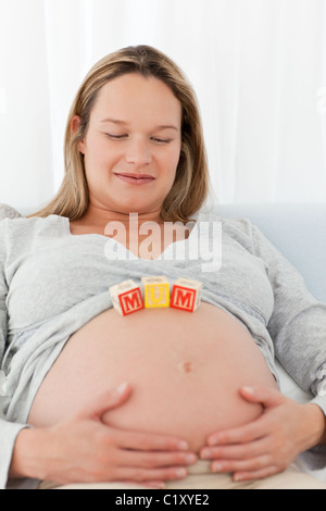 Jolie femme enceinte avec maman lettres sur son ventre Banque D'Images