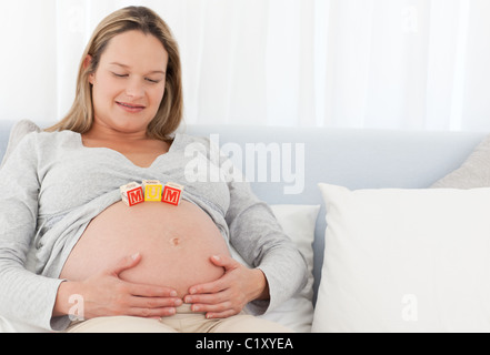 Jolie femme enceinte avec des lettres sur son ventre Banque D'Images