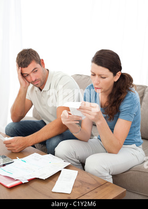 Souligné couple leurs comptes assise sur le canapé Banque D'Images