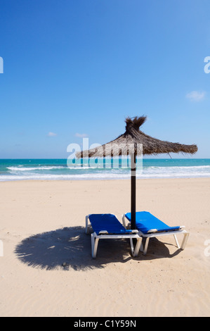 Chaises longues et parasol sur une plage Méditerranéenne espagnole. Dehesa de Campoamor, Orihuela, Alicante province, Spain. Banque D'Images