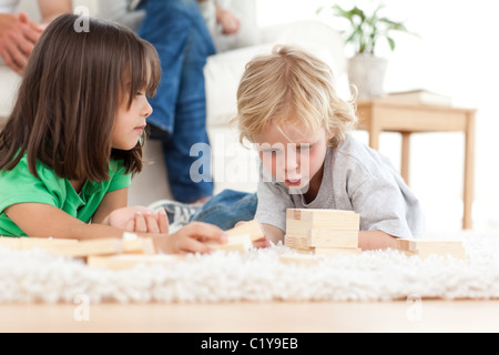 Adorable petit garçon jouant aux dominos avec sa soeur sur le sol Banque D'Images