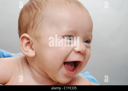 Close up of cute baby qui est sourire, rire et à la recherche sur le côté. Banque D'Images