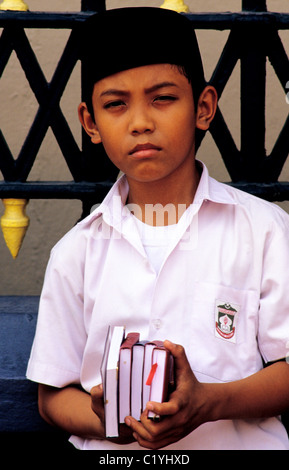 Singapour. Garçon de l'école musulmane se tient juste en face de la Mosquée Sultan avec l'Islam l'étude religieuse books.. 2008 © Bob Kreisel Banque D'Images