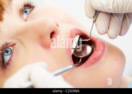 Photo de femme bouche ouverte pendant l'inspection orale avec crochet et miroir Banque D'Images