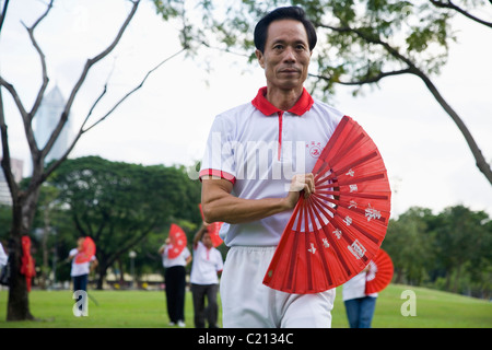 Matin t'ai chi avec ventilateur dans le Parc Lumphini. Bangkok, Thaïlande Banque D'Images