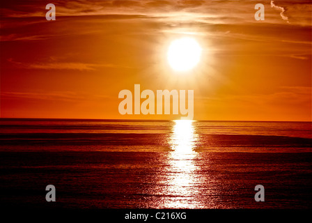 Un coucher du soleil orange brillant et reflétant sur l'océan Banque D'Images