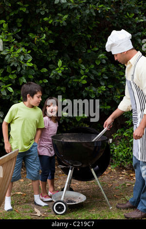 Famille ayant un barbecue dans le jardin Banque D'Images
