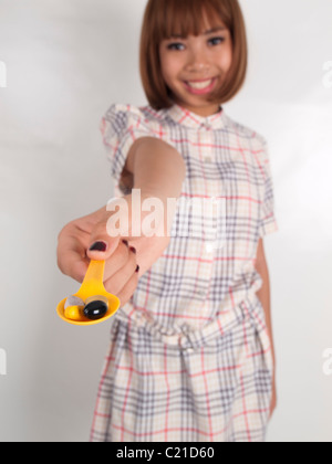 Une femme debout regarde vers d'un appareil photo avec hand holding spoon plein de vitamines multiples Banque D'Images