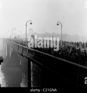 Années 1950. Un smog s'Londres comme de grandes foules de personnes marcher sur Waterloo Bridge, sur leur façon de travailler dans ce tableau historique. Banque D'Images