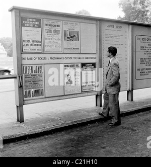 Le 1950 juin, Londres, un homme nouvellement arrivé immigrant en Grande-Bretagne étudie un comité d'affichage énumérant des événements au Royal Albert Hall, Yehudi Menuhin apparaissant. Banque D'Images