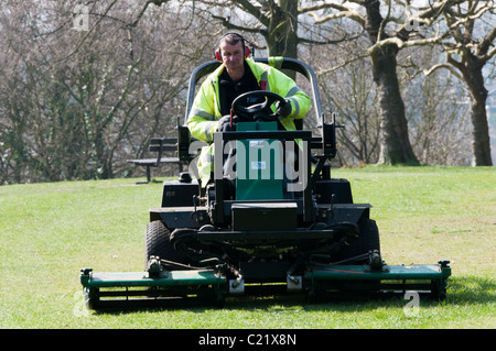 Un jardinier tond le gazon dans un parc public à Bromley, Kent Banque D'Images