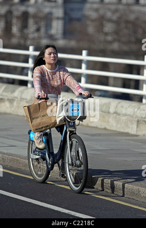 Une femme tenant un sac et une circonscription Boris Bike à Londres, en Angleterre, un jour ensoleillé Banque D'Images