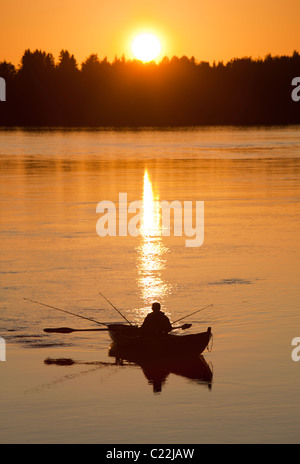 Pêche en bateau à rames / skiff / canot au coucher du soleil sur la rivière Oulujoki Finlande Banque D'Images