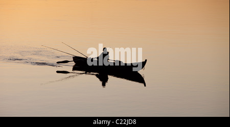 Pêche en bateau à rames / skiff / canot au coucher du soleil sur la rivière Oulujoki Finlande Banque D'Images