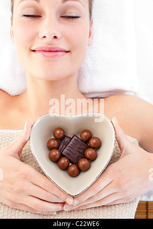 Femme tenant un bol lumineux en forme de cœur avec du chocolat Banque D'Images