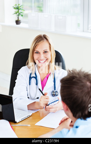 Smiling female doctor écrit une ordonnance pour son patient dans le bureau Banque D'Images