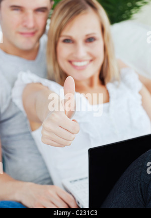 Jeune couple travaillant sur un ordinateur portable avec une petite amie thumbs-up Banque D'Images