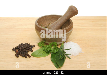 Les fines herbes, sel de mer, poivre en grains avec un pilon et mortier sur une planche en bois Banque D'Images