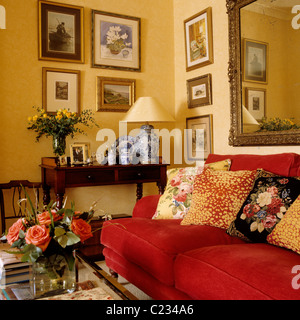 Coussins à motifs sur canapé rouge dans la salle de séjour avec un intérieur traditionnel anglais pays Banque D'Images