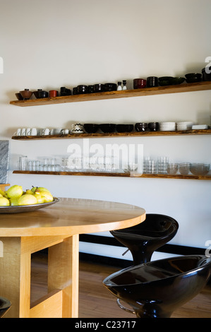 Stefano Giovannoni tabourets à une table ovale en bois en cuisine avec vaisselle ouvert étalage Banque D'Images