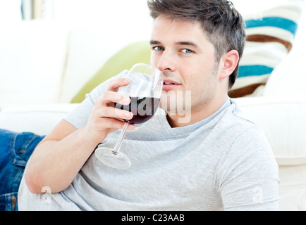 Bel homme allongé sur le sol de boire du vin Banque D'Images