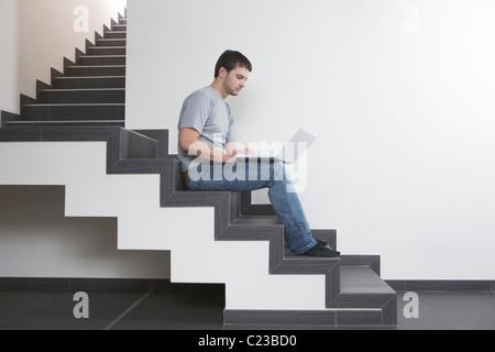 Jeune homme est assis sur l'escalier avec coffre Banque D'Images