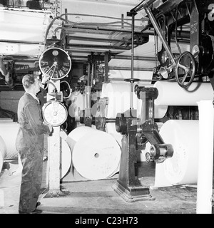 Années 1950. L'Angleterre. Travailleur gère une grande presse à imprimer dans ce tableau historique par J Allan l'argent comptant. Banque D'Images