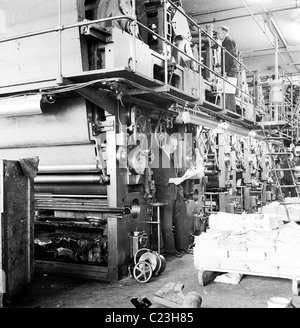 Années 1950. L'Angleterre. Stand travailleur par une grande banque de presses à imprimer ce tableau historique par J Allan l'argent comptant. Banque D'Images