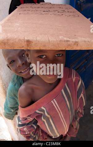 Tablette d'écolier portant sur sa tête dans l'Kibédoué quart de Bobo Dioulasso Banque D'Images