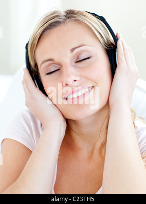 Jeune femme rayonnante portant des écouteurs pour écouter de la musique Banque D'Images