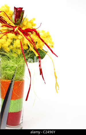 Rose rouge dans un bouquet avec vase en verre jaune mimosa photographié sur fond blanc Banque D'Images