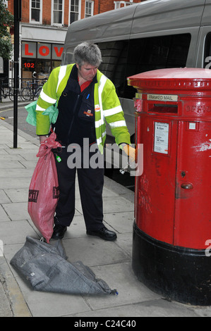Un postier recueille un billet sur un boite aux lettres dans le centre de Londres après la grève national post a été mis en attente, Londres, Angleterre - Banque D'Images