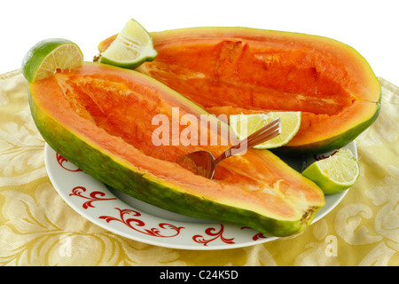 Gros fruits rouge des Caraïbes est préparé et prêt à manger avec des quartiers de lime. La papaye mûre et fraîche avec orange couper des morceaux de lime sur une plaque Banque D'Images