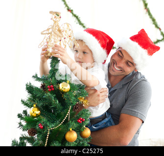 Heureux père d'aider son fils à mettre un ange sur l'arbre de Noël Banque D'Images