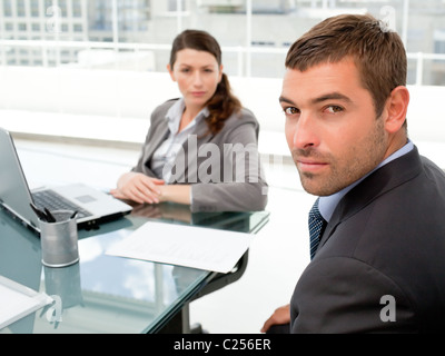 D'affaires graves assis autour d'une table et regardant la caméra Banque D'Images