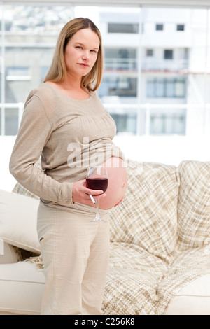 Futur maman sérieuse avec un verre de vin et de cigarettes Banque D'Images