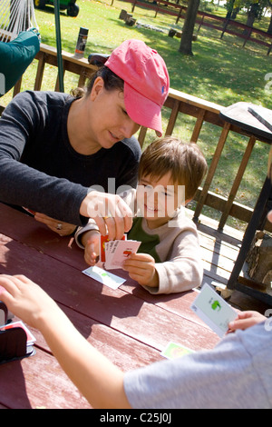 Maman aider son playing card game des pommes avec des pommes à l'extérieur sur le pont. Clitherall Minnesota MN USA Banque D'Images