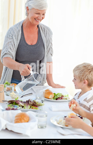 Grand-mère de donner à son petit-fils de l'eau au cours d'un repas Banque D'Images