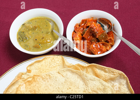 Une plaque de pappadums indien avec bols de mangue verte et de chaux blanc cornichons. Banque D'Images