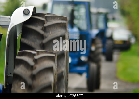 Rangée de trois tracteurs sur une route de campagne Banque D'Images