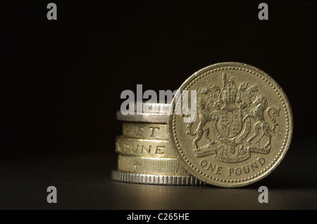 Une pile de pièces de monnaie britanniques avec la livre coin debout sur elle. Banque D'Images