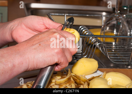 Woman Peeling une nouvelle pomme de terre avec une éplucheuse de pommes de terre Banque D'Images
