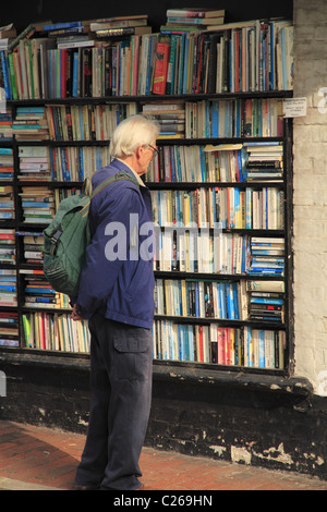 Un homme parcourant les rayons de livres à l'extérieur d'une librairie de seconde main à Eastbourne, East Sussex, Angleterre. Banque D'Images