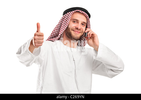 Parler arabe souriant sur un téléphone mobile et giving thumb up Banque D'Images