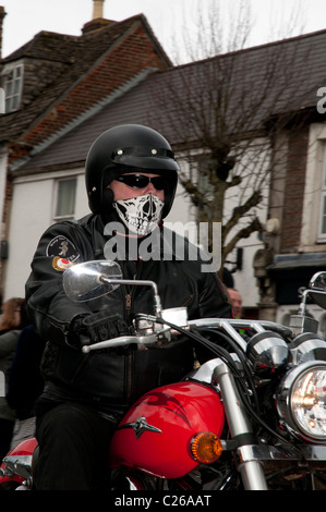 Motocycliste portant son casque noir et la nouveauté crâne masque de visage rides sa moto le long de Wootton Bassett High Street Banque D'Images