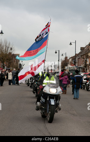 Motocycliste chevauche son vélo et drapeaux le long de Wootton Bassett High Street, afin de recueillir des fonds dans le trajet de respect parade. Banque D'Images