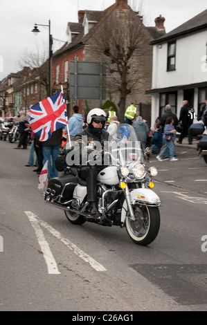 Harley Davidson patriotique motocycliste battant Union Jack flag comme il monte son vélo vers le bas Wootton Bassett High Street Banque D'Images